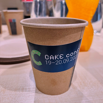 A coffee cup from CAKE conf 2025 with a sticker on it